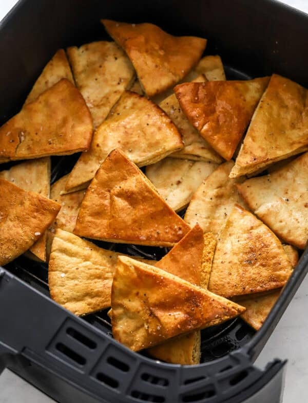 Pita chip triangles cooked in an air fryer basket.
