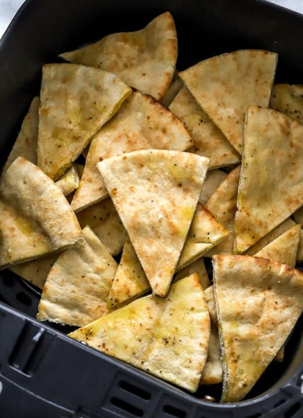 Uncooked pita chips in the air fryer basket.