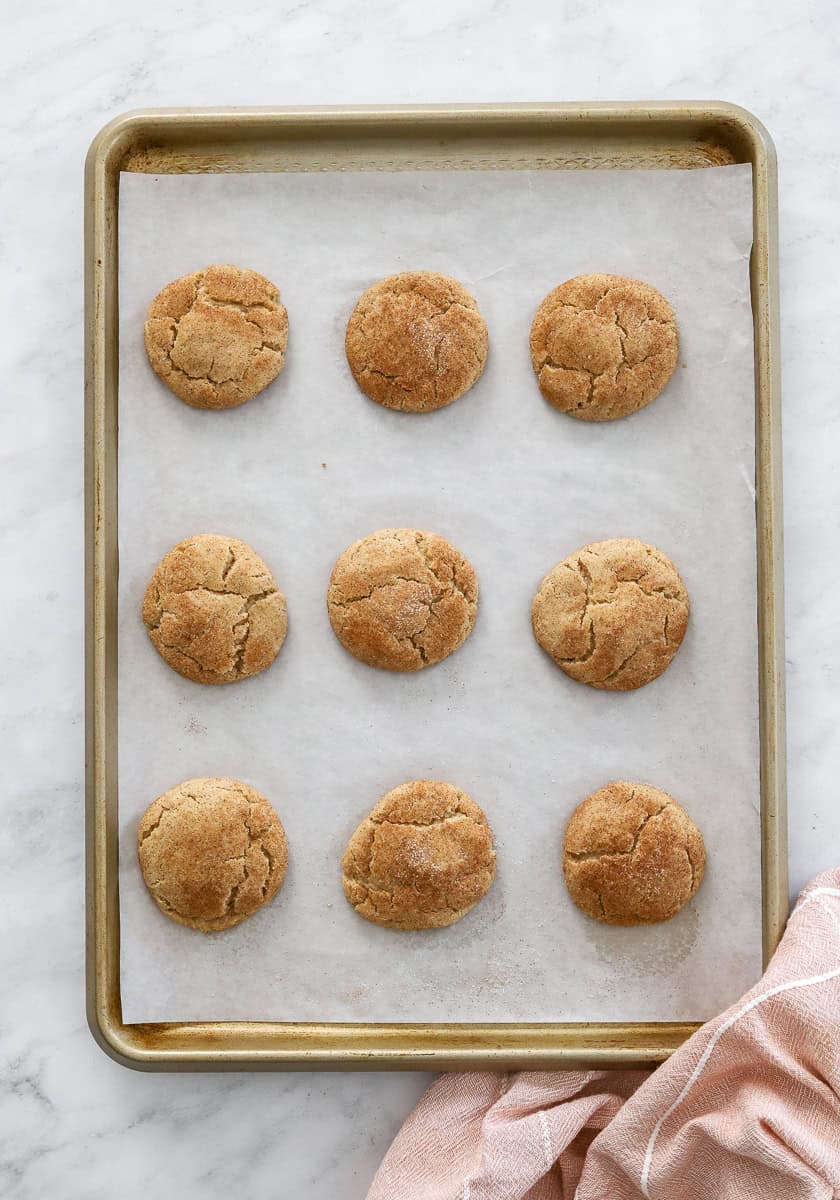 Baking sheet filled with baked cookies with cinnamon on them.