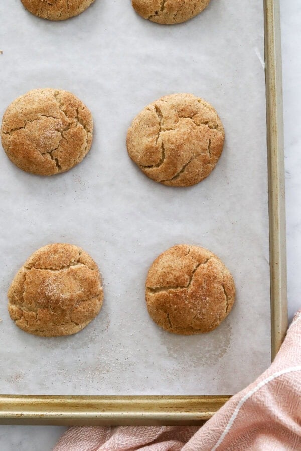 Cinnamon cookies on a baking pan with a pink towel in front of it.