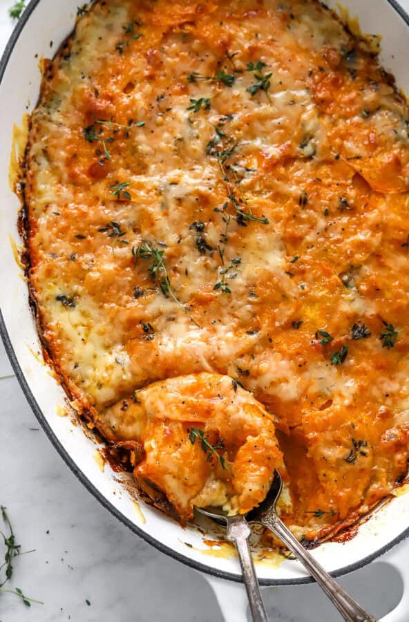 Baked sweet potato gratin with serving spoons in the dish.