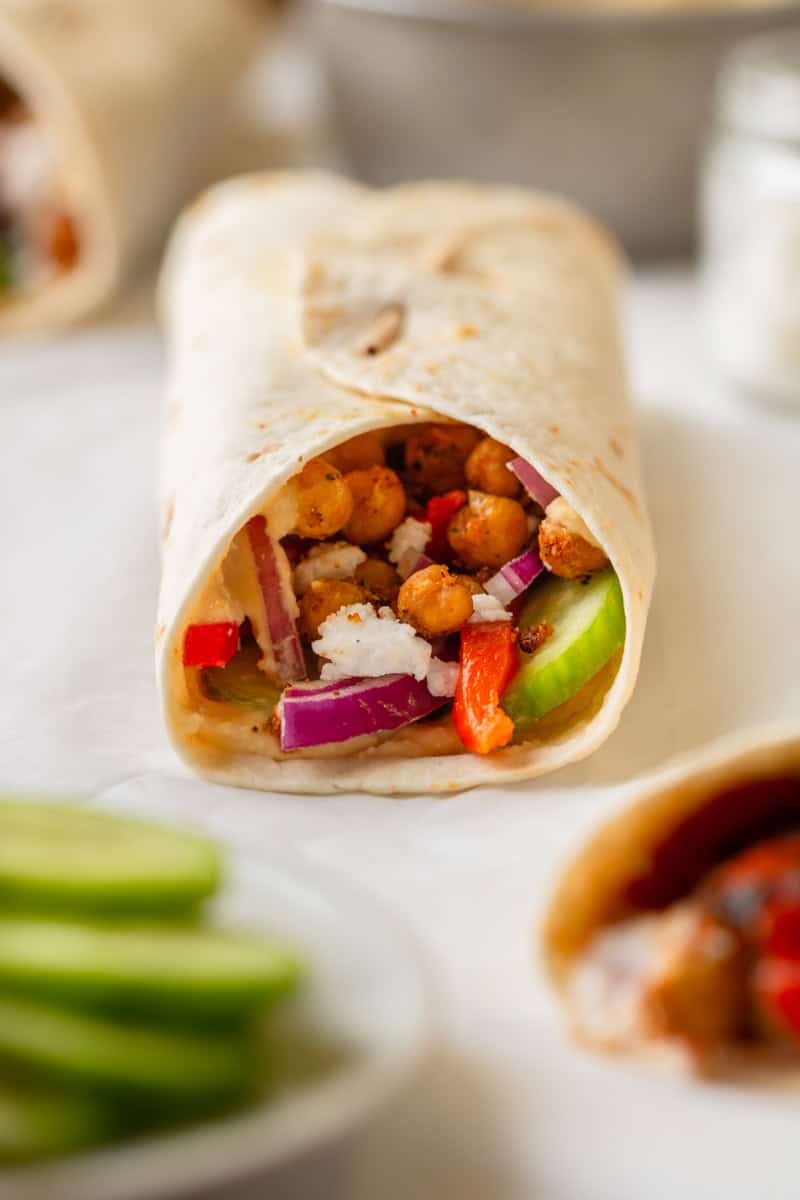 Chickpea humus veggie wrap in a flour tortilla on a plate. 