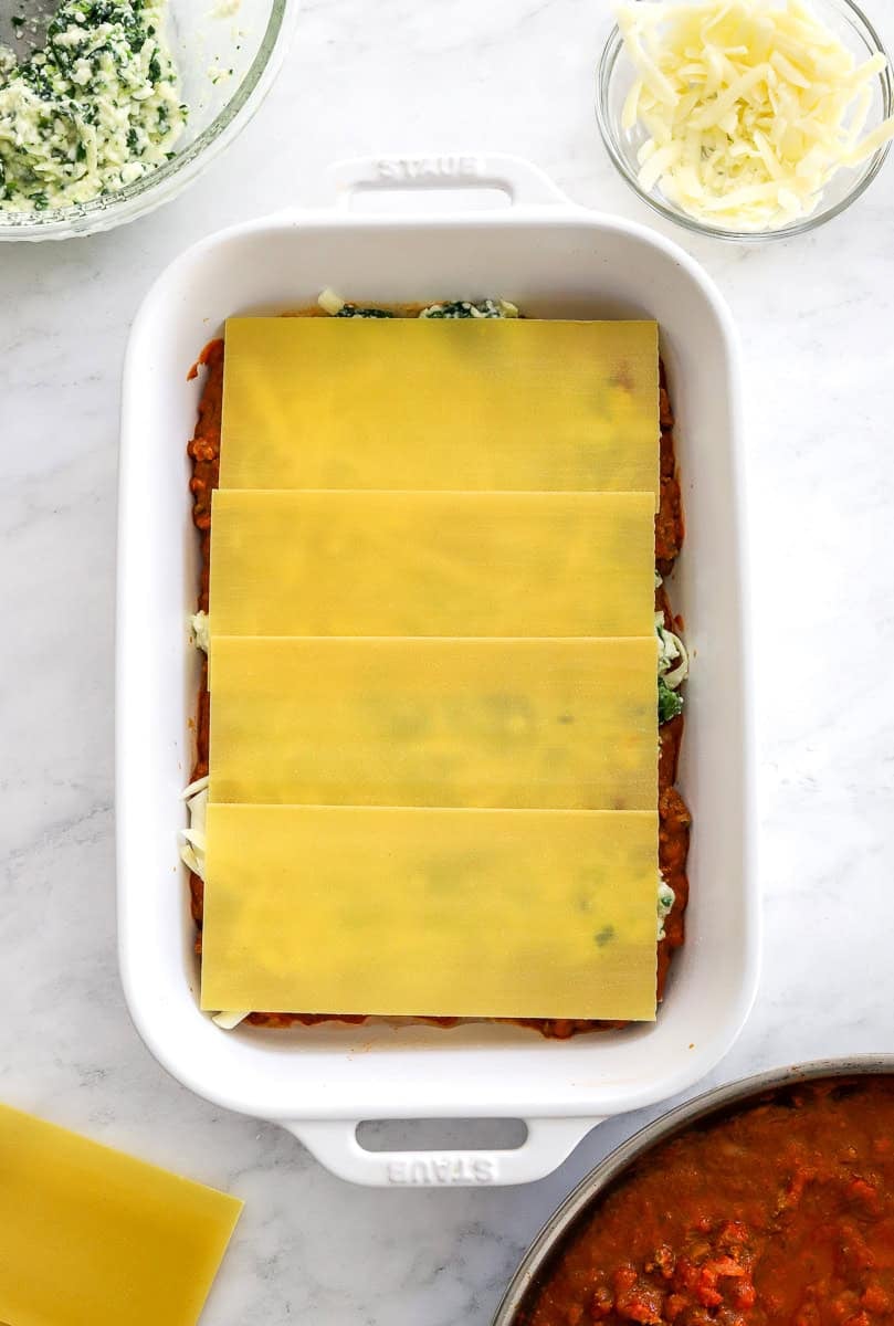 Uncooked layered lasagna with the noddle layer on the top.