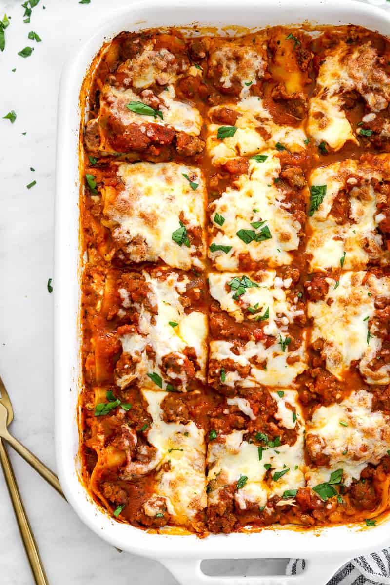 Pan of baked cottage cheese lasagna with gold serving ware next to it.