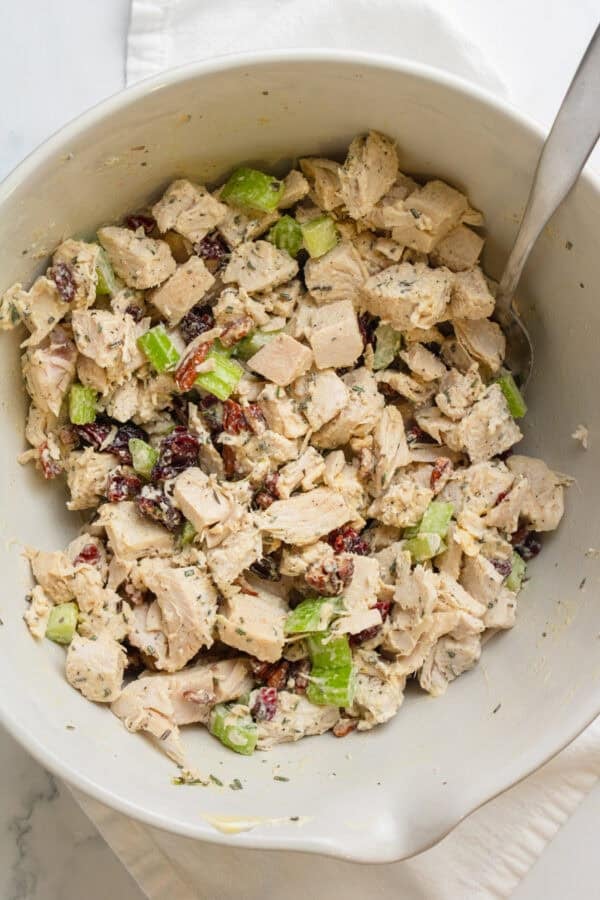 Mixed turkey salad with leftover turkey in a mixing bowl with a spoon in the bowl.