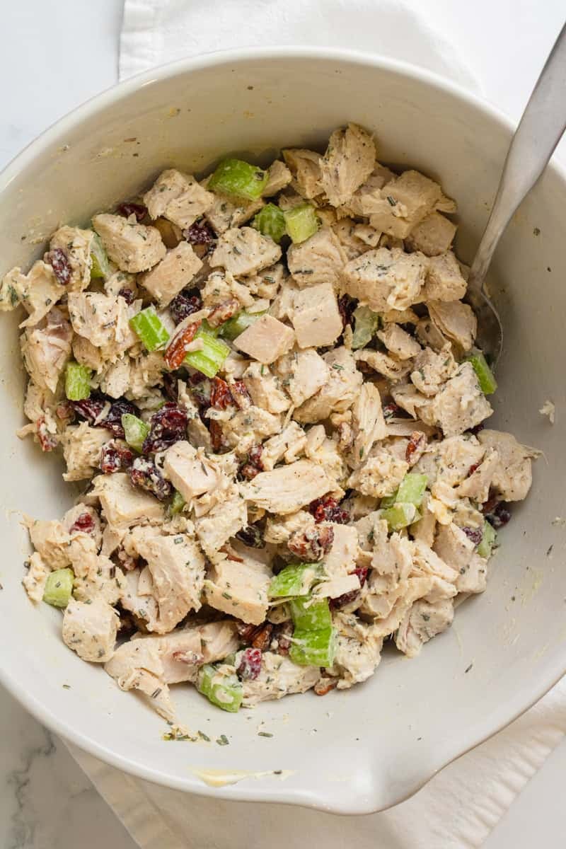 Mixed turkey salad with leftover turkey in a mixing bowl with a spoon in the bowl.