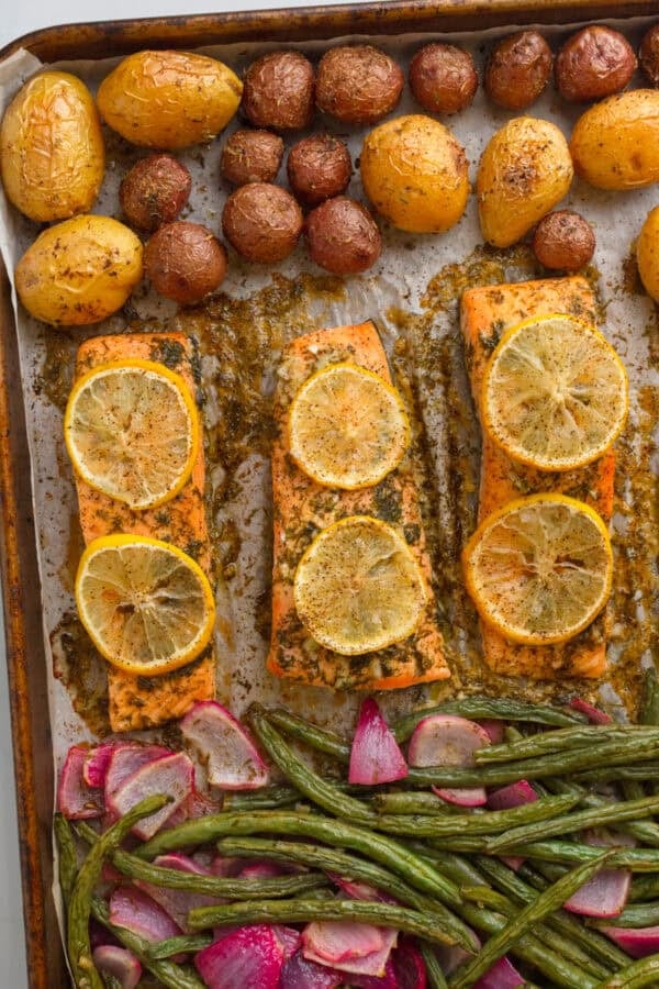 Sheet pan full of baked salmon with potatoes and green beans.