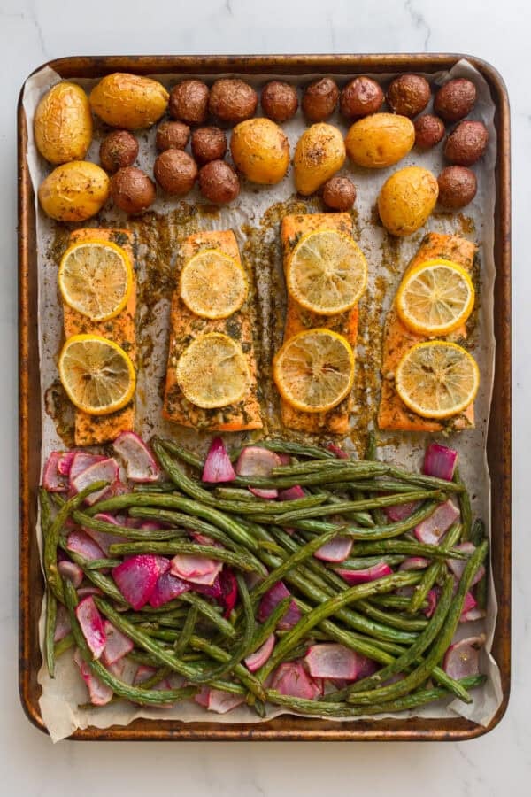 Sheet pan full of baked salmon with potatoes and green beans.
