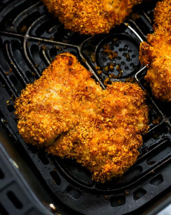 Golden fried chicken cooked in the air fryer in an air fryer basket.