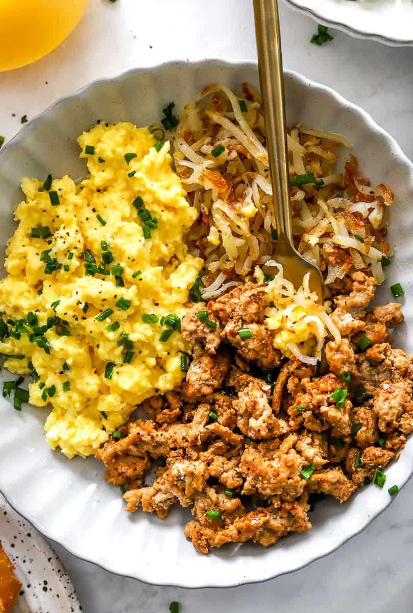 Scrambled eggs, cooked ground turkey, and browned shredded potatoes in a bowl.