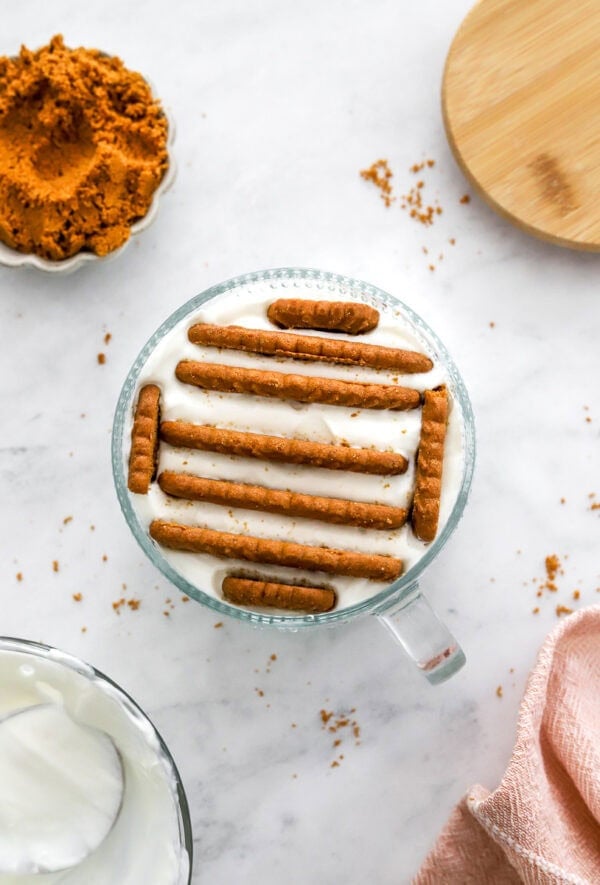 Glass bowl of Greek vanilla yogurt with biscoff cookies nestled in the yogurt.