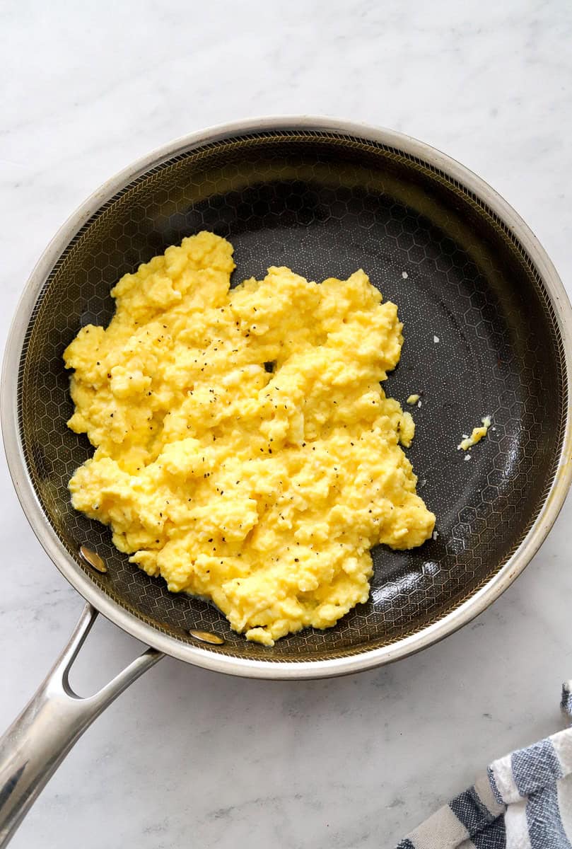 Cooked scrambled eggs in a sauté pan.