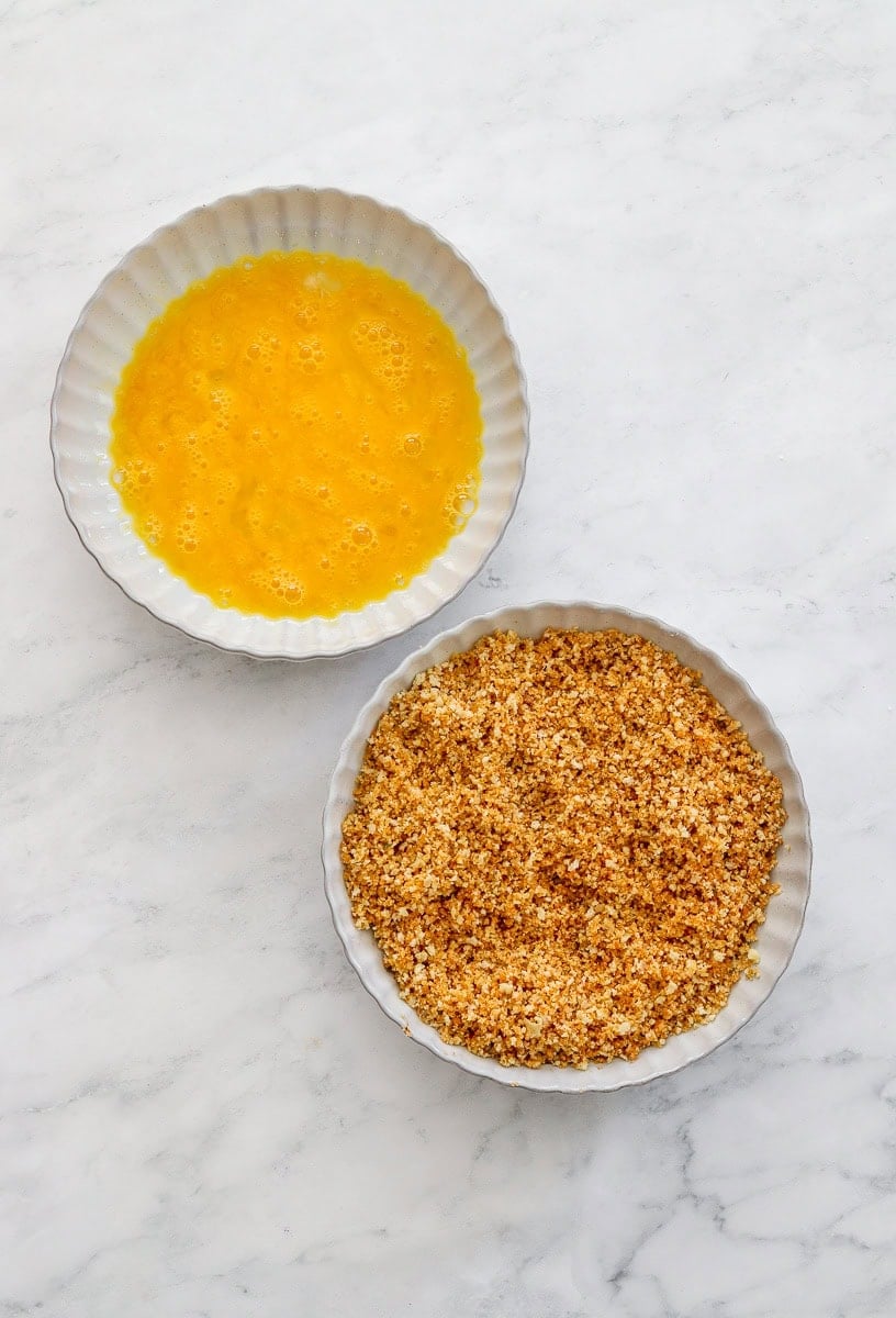 Bowl with whisked eggs with a bowl of breadcrumbs mixture in front of it.