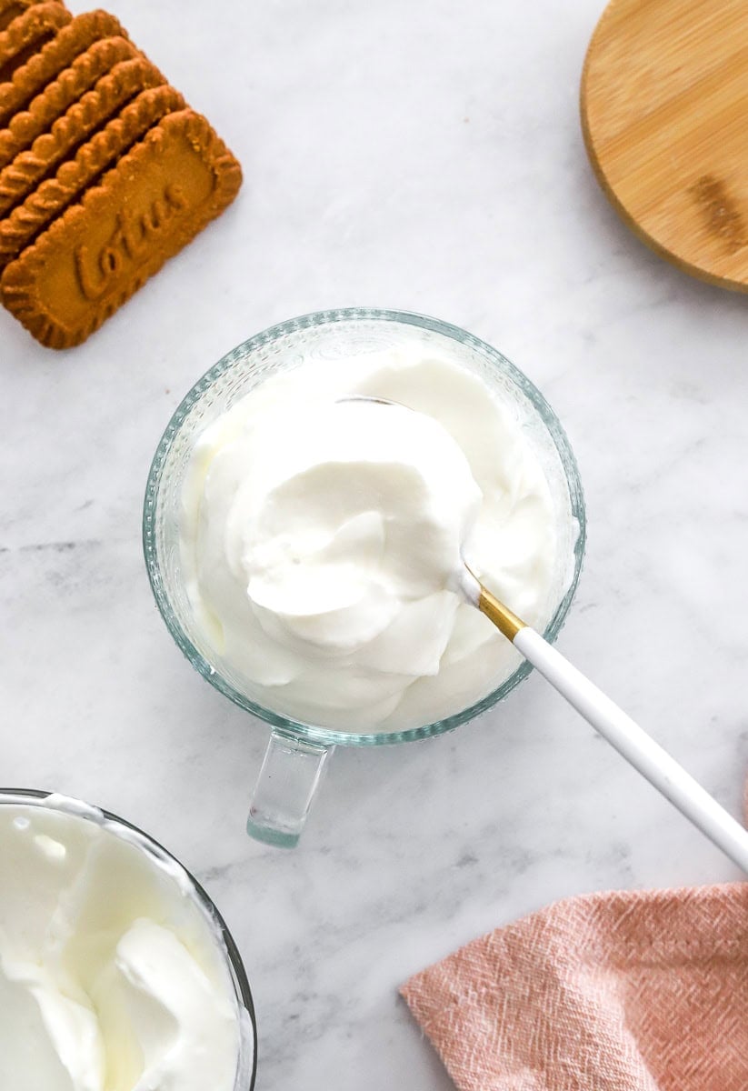 Glass dish filled with vanilla Greek yogurt with a spoon in the dish. 