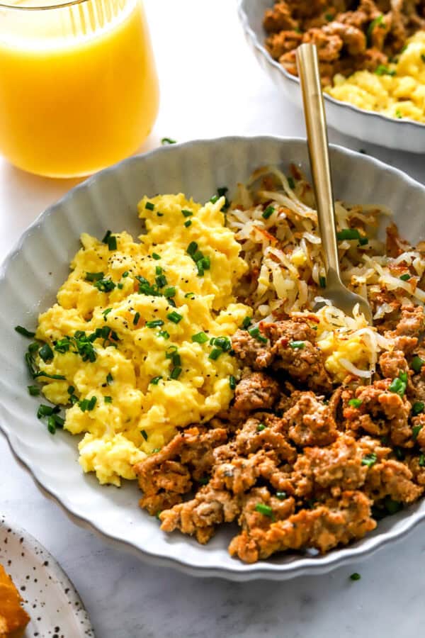 Egg scramble and meat breakfast bowl with a fork in bowl with it.