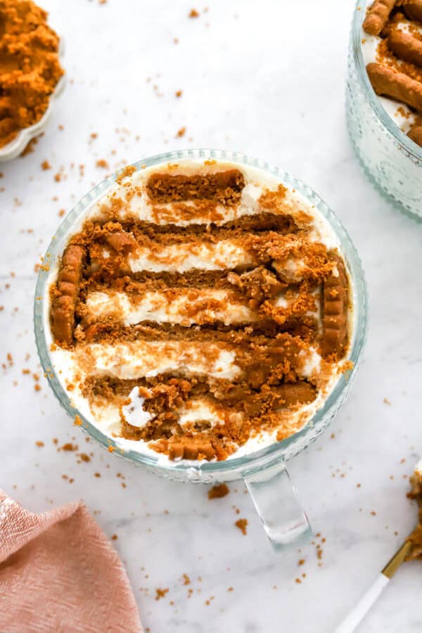 Jar filled with greek yogurt cheesecake topped with crushed Biscoff cookies.