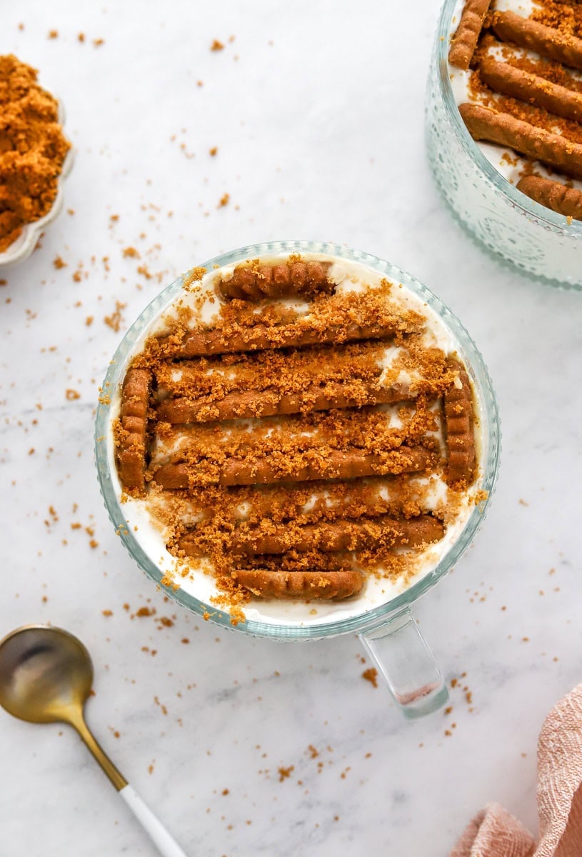 Glass dish with greek yogurt with cookies in it and cookie crumbs on top of it with another one behind it.