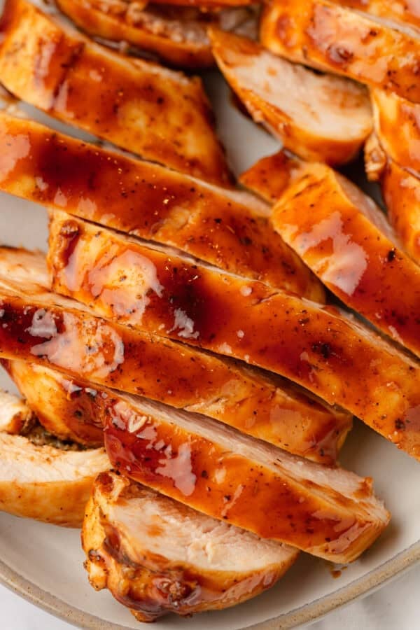 Juicy sliced cooked bbq chicken breast on a plate.