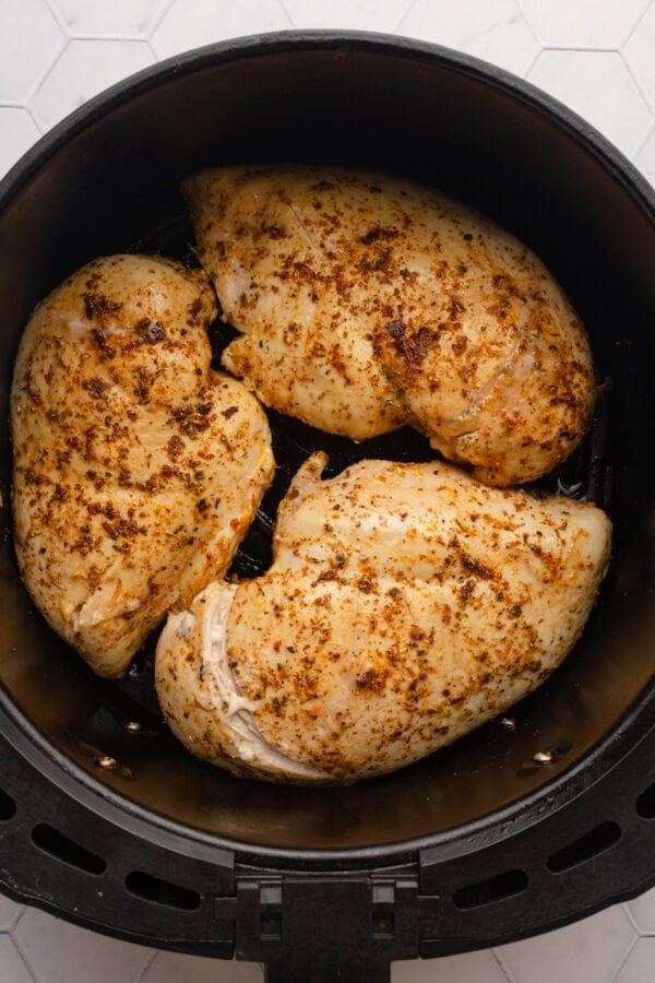 Cooked seasoned chicken breast in round air fryer basket.