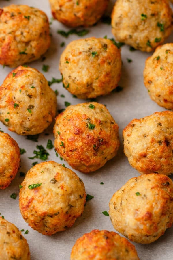Cooked golden air fried chicken meatballs on a lined pan.