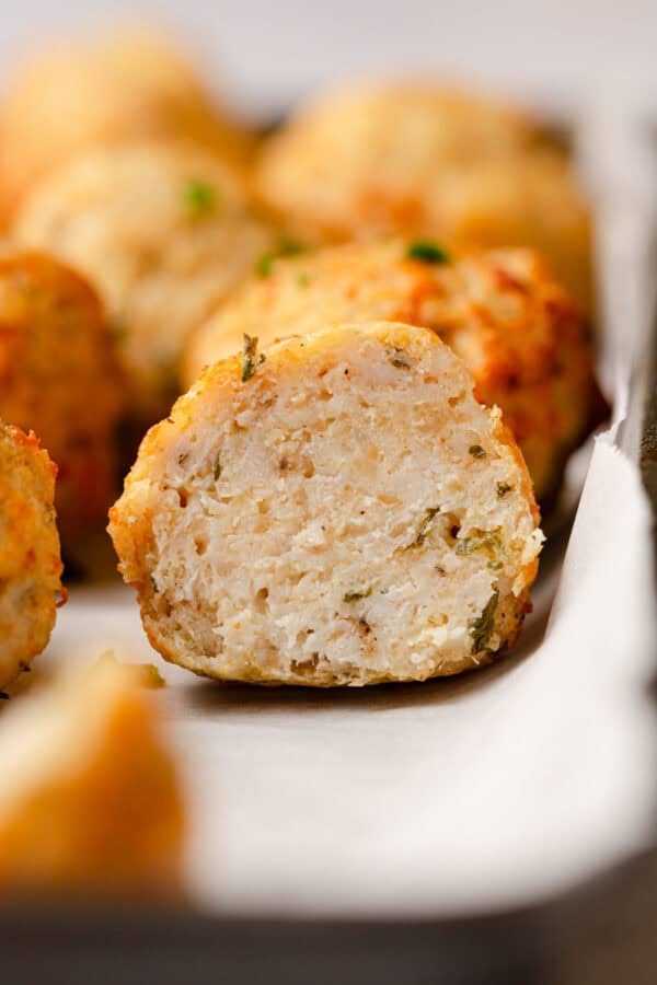 Insided of a cut ground chicken meatballs with more behind it.