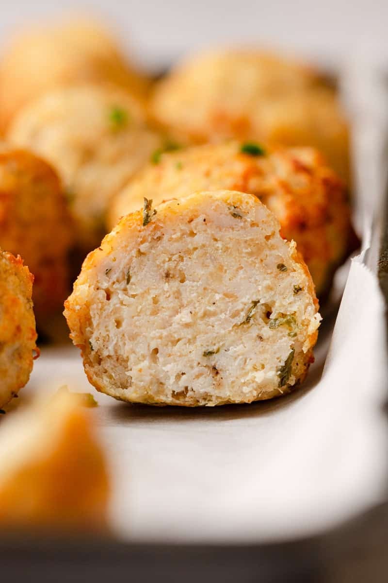 Insided of a cut ground chicken meatballs with more behind it.