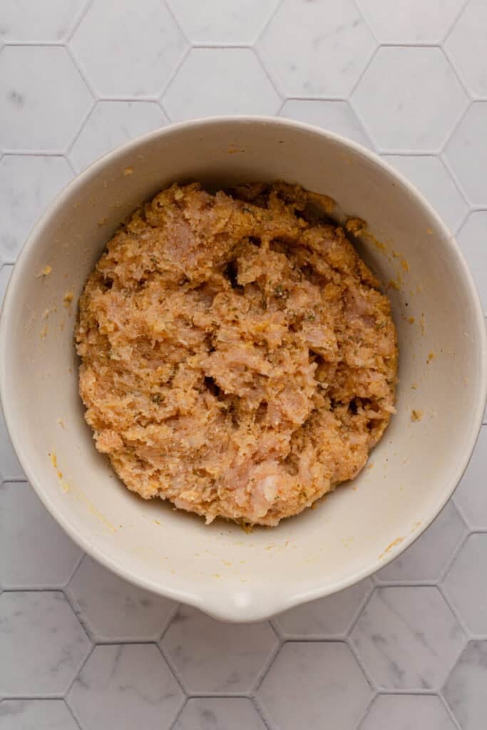 Raw ground chicken meatball mixture in mixing bowl.