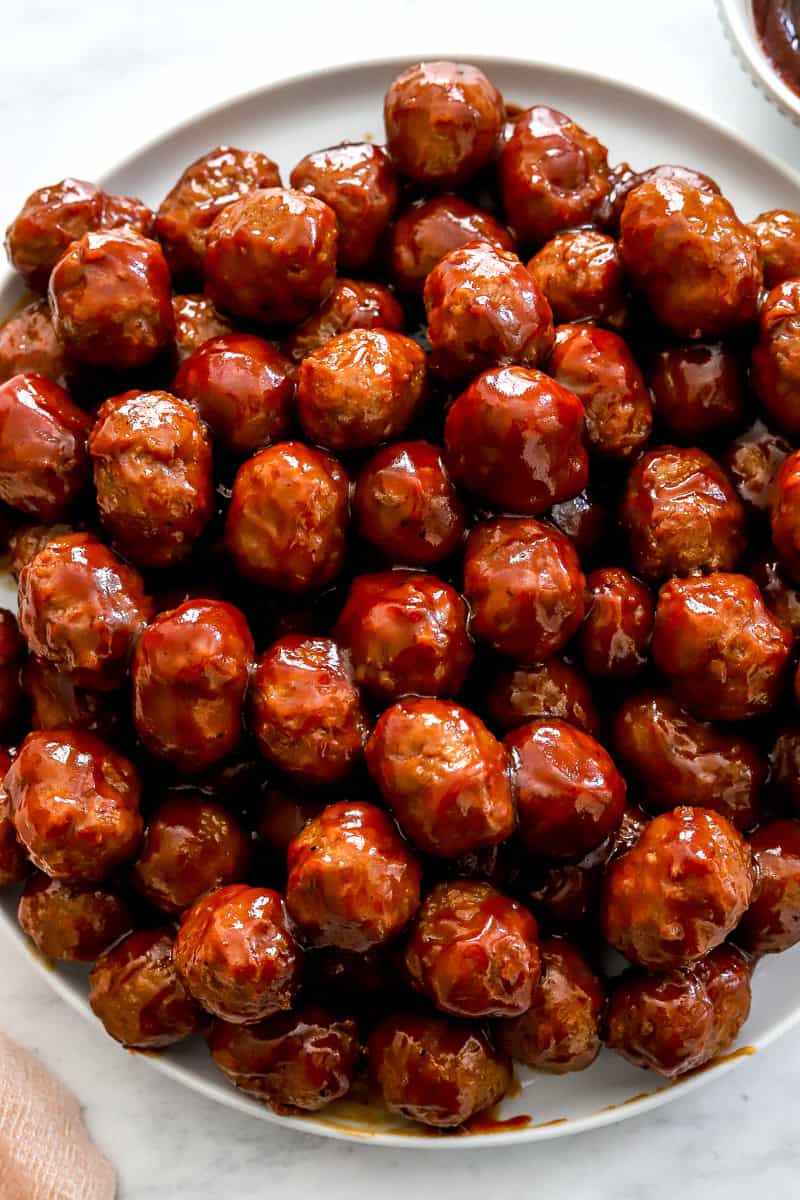 Plate of crockpot BBQ meatballs covered in BBQ sauce.