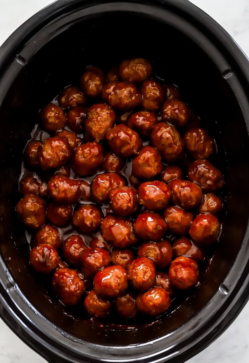 Cooked meatballs covered in BBQ sauce in a crockpot. 