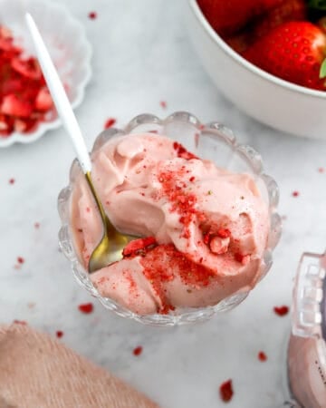 Ninja creami strawberry ice cream scooped from the Ninja Creami in a glass ice cream dish with a spoon in the dish.