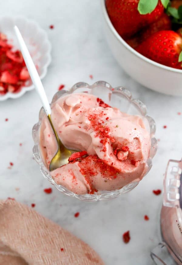 Ninja creami strawberry ice cream scooped from the Ninja Creami in a glass ice cream dish with a spoon in the dish.