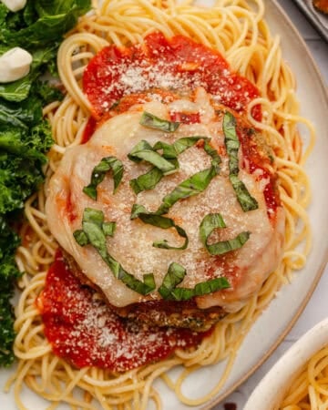 Piece of breaded mushroom parm on top of pasta with red sauce around it.