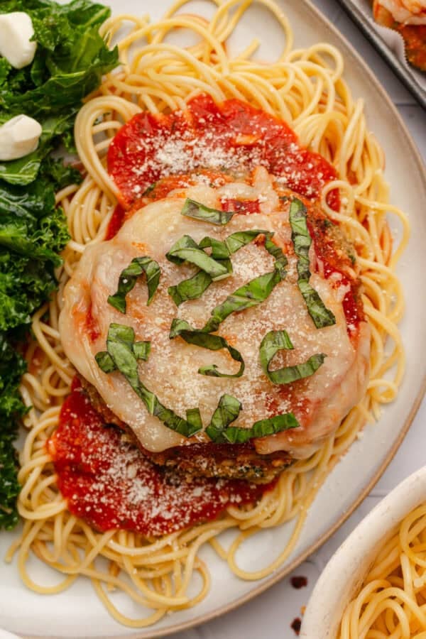 Piece of breaded mushroom parm on top of pasta with red sauce around it.