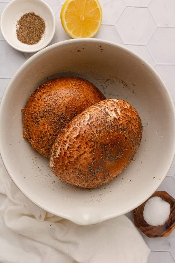 Marinated whole portobello mushrooms in a bowl.