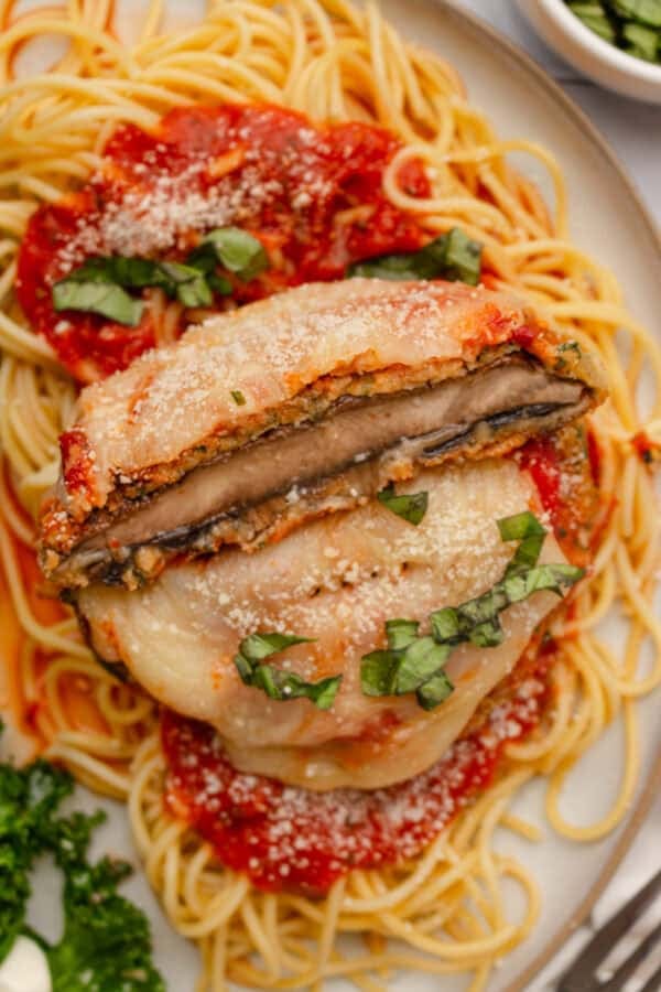 Sliced breaded mushrooms topped with melted cheese on top of cooked spaghetti and sauce.