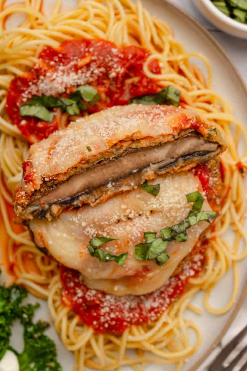 Sliced breaded mushrooms topped with melted cheese on top of cooked spaghetti and sauce.