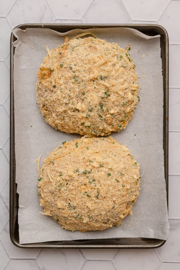 Parmesan breading coated portobello mushroom caps on a lined pan.