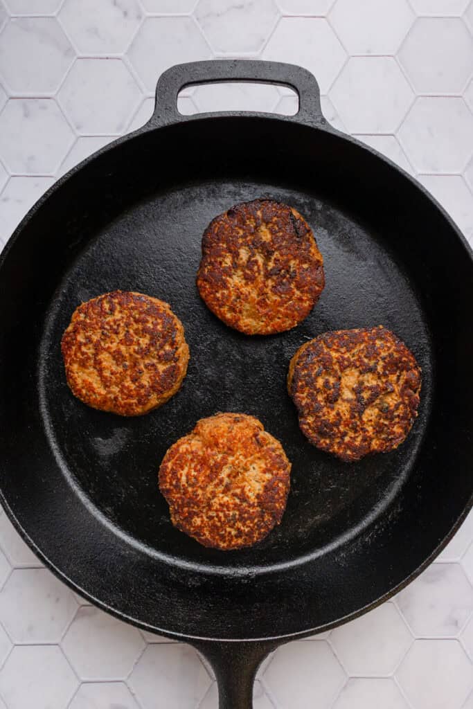 Cooked homemade turkey burgers in a cast iron pan. 