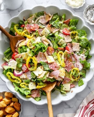 Large bowl filled with the best Italian sub salad with wood spoons in the bowl.