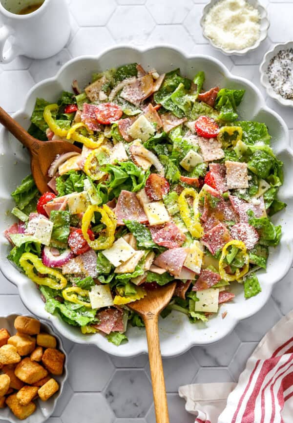 Large bowl filled with the best Italian sub salad with wood spoons in the bowl.