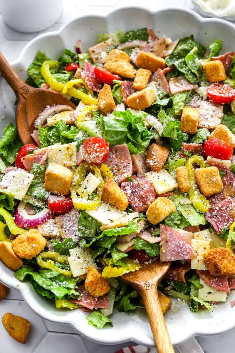 Tossed meat and cheese deli style salad in a salad bowl topped with croutons and grated parmesan cheese. 