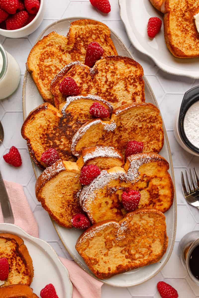 Platter of protein powder French toast topped with powdered sugar and fresh raspberries. 