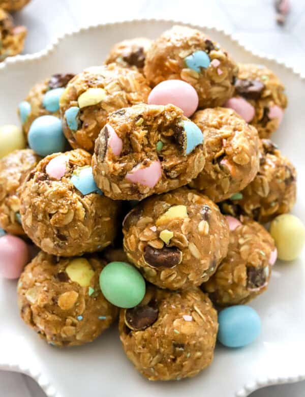 Rolled energy bites on a white plate with Easter candy around it.