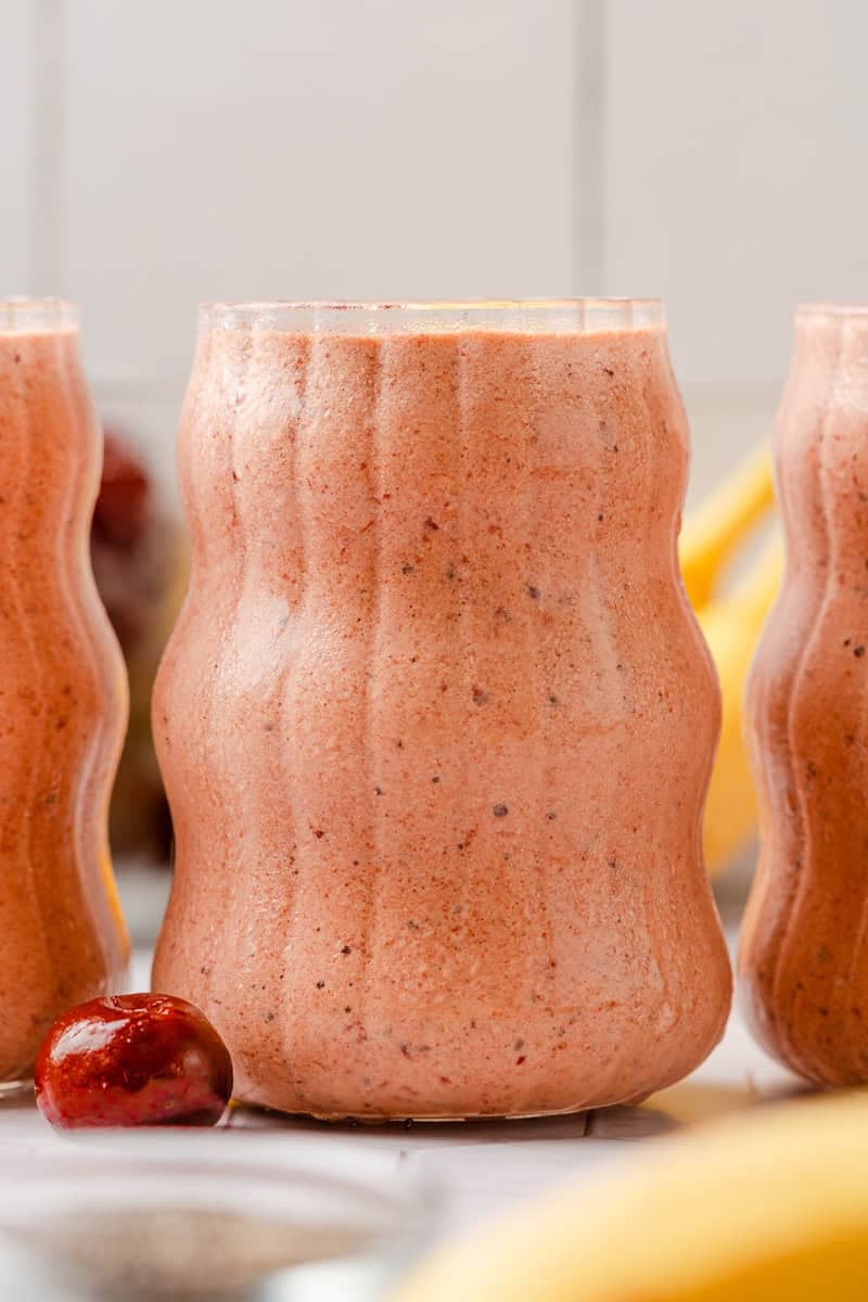 Glass filled with creamy cherry smoothie with another one next to it. 