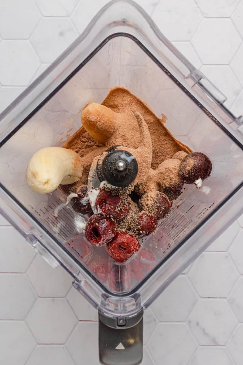 Frozen cherry smoothie ingredients in a blender before being blended.