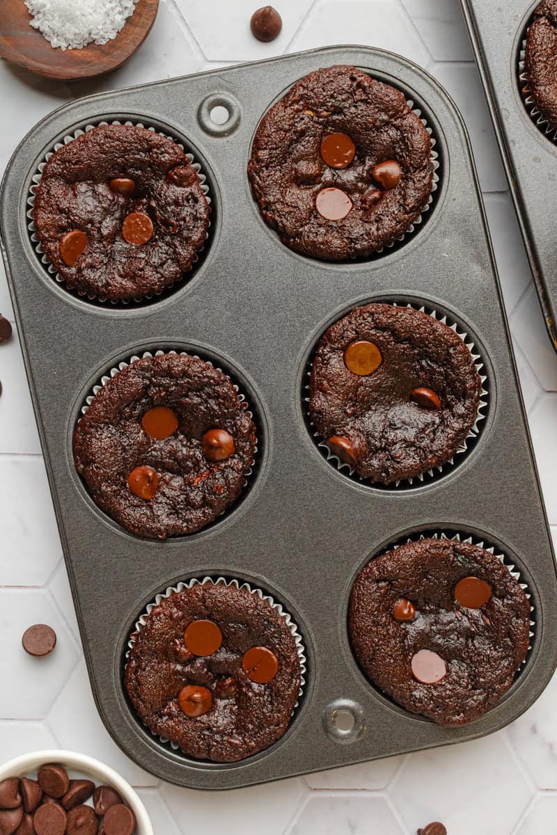 Baked double chocolate zucchini chocolate chip muffins in a silver muffin pan. 