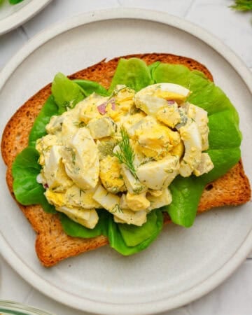 Healthy egg salad on whole grain toast on a plate.