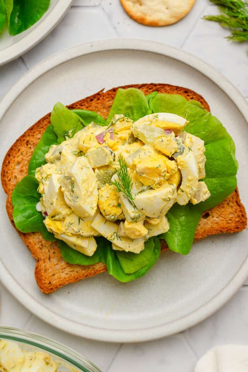 Healthy egg salad on whole grain toast on a plate. 