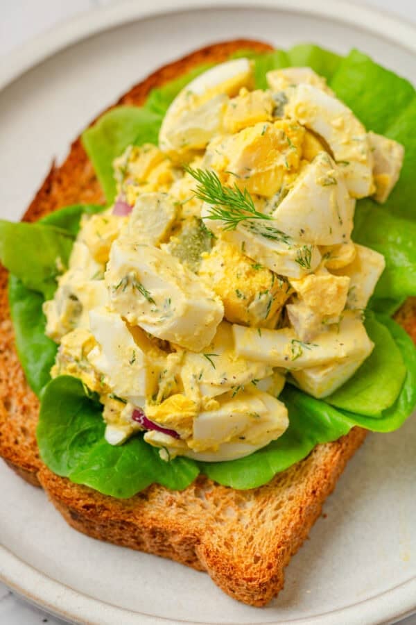 Toasted bread with egg salad on it on a plate.