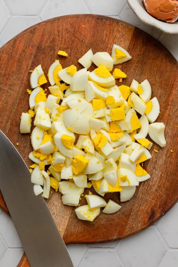 Chopped hard boiled eggs on wood cutting board.